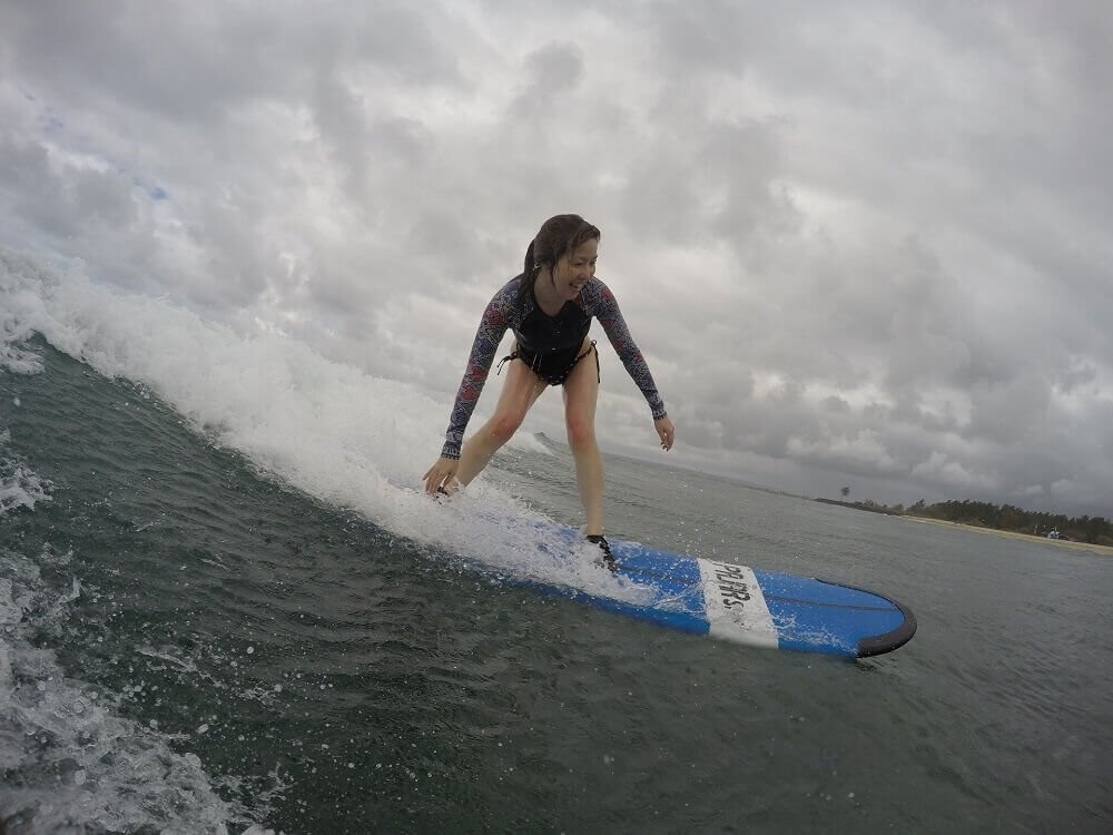 Beginner surfer standing on a surfboard at Cnggu Beach Bali